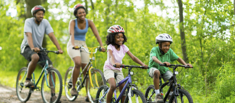 African American family cycling on a forest trail.